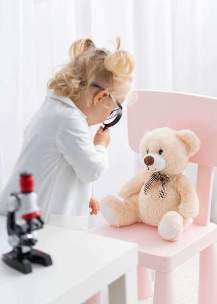 Side view of cute toddler with microscope and magnifying glass