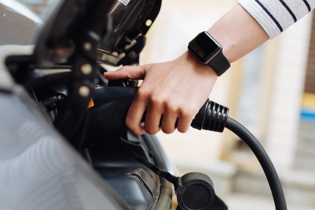 The side view of a delicate female hand plugging in a charger into the battery system