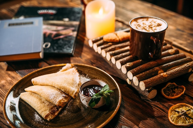 Side view on delicious warming cappuccino coffee with cinnamon in a mug on the wooden board and pancakes