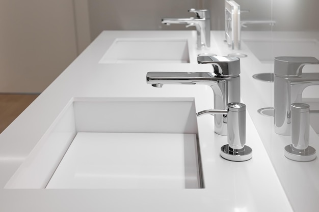 Side view of double white sink with large and small taps for filtering running water for drinking