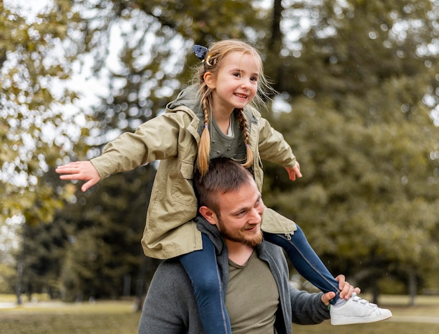 Side view father carrying girl on shoulders