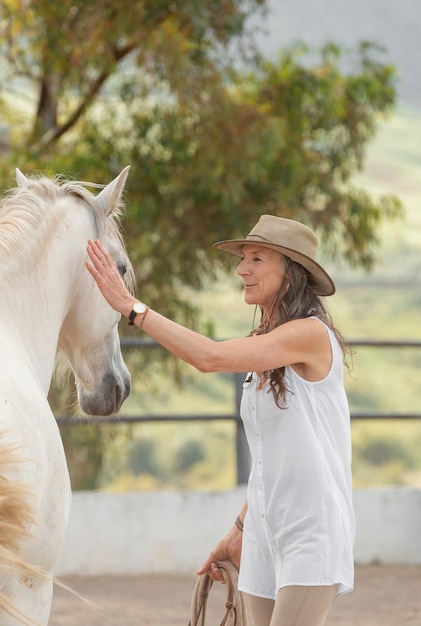 Side view of female farmer with her horse at the ranch