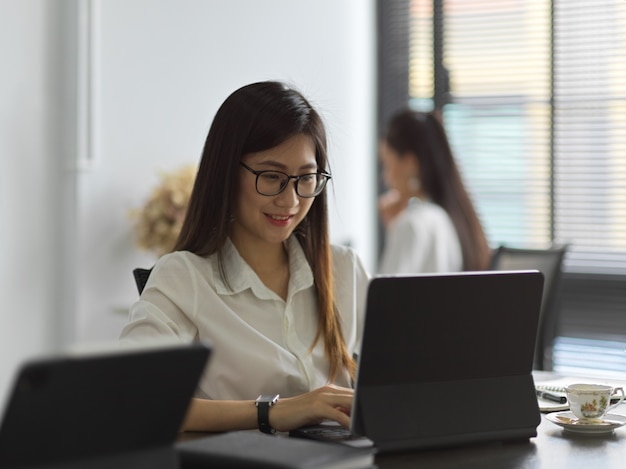 Side view of female typing office worker working with laptop in office room