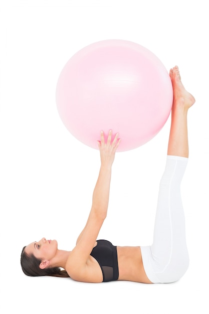 Side view of a fit woman exercising with fitness ball