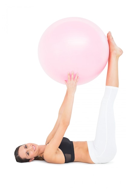 Side view of a fit woman exercising with fitness ball