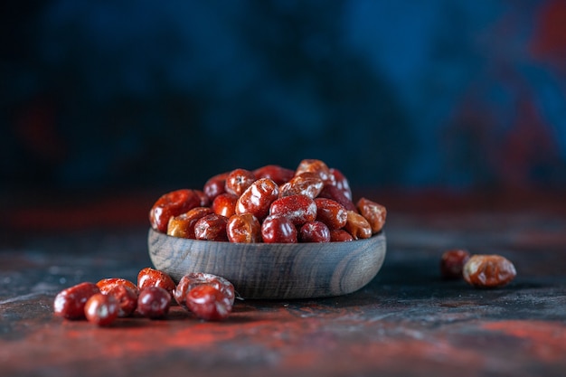 Side view of fresh raw silverberry fruits inside and outside of a bowl on mix colors background with free space