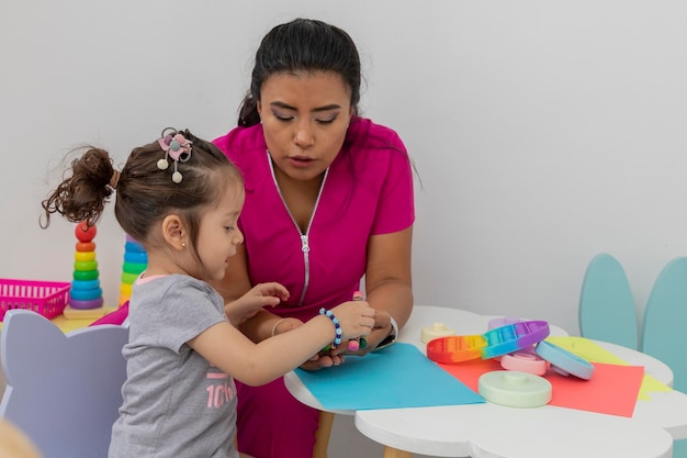 Side view of a girl drawing with a female pediatrician doctor in her office