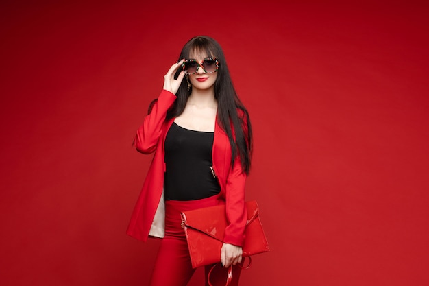 Side view of glamorous brunette posing in red suit