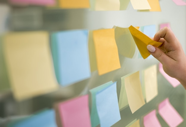 Side view of hand putting sticky notes on window