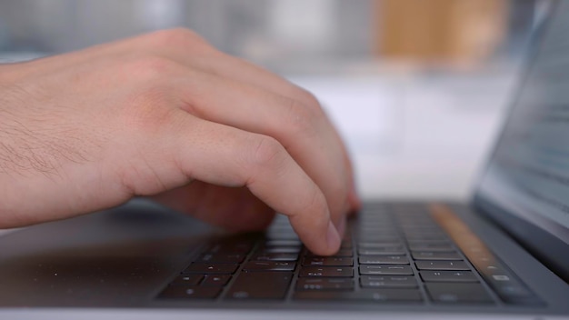 Side view of hands pressing keys of black laptop keypad action close up of a keayboard and man hands