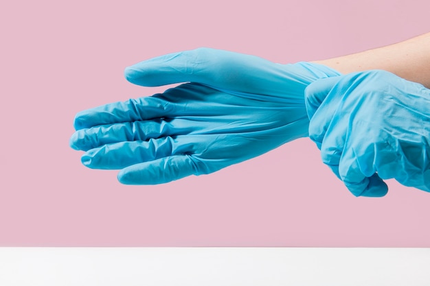 Side view of hands putting on surgical gloves