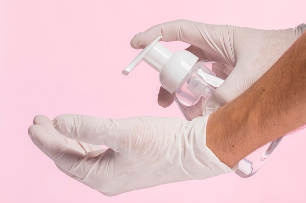 Side view of hands with surgical gloves using disinfectant