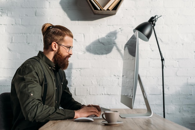 Side view of handsome businessman using computer in office