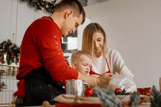 Side view of happy funny family mother father and little son bake christmas cookies on cozy kitchen