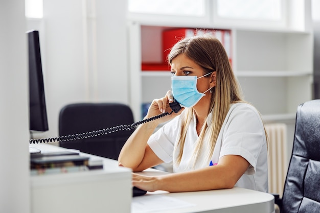 Side view lab assistant sitting in laboratory and having emergency call about covid-19 positive patient.