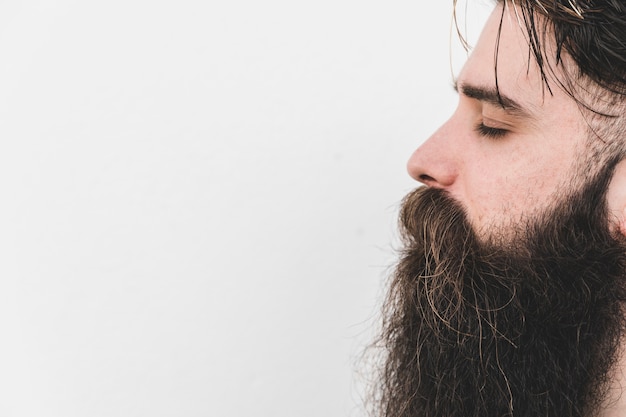 Side view of a long bearded man closing his eye against white backdrop