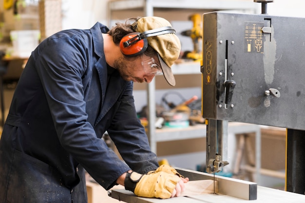 Side view of a male carpenter taking measurement on workbench