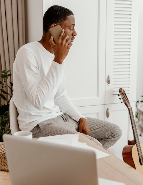 Side view of male musician talking on the smartphone next to guitar