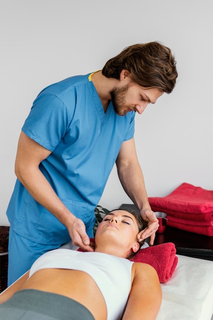 Photo side view of male osteopathic therapist checking female patient's neck spine