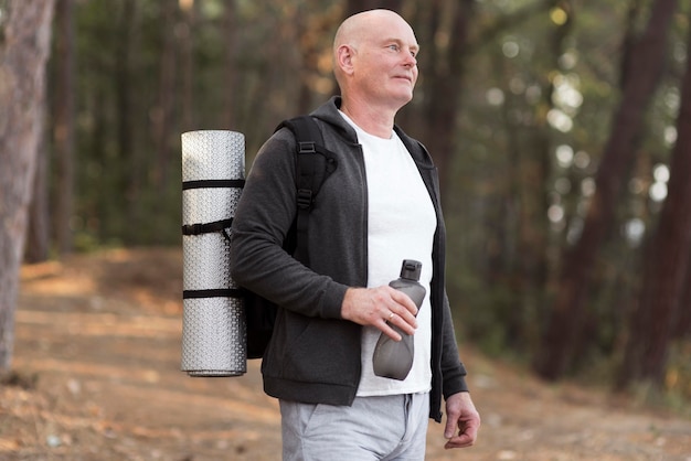 Side view man carrying yoga mat