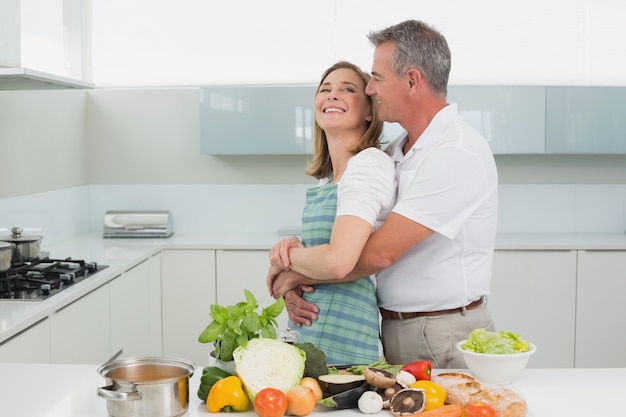 Side view of a man embracing woman in kitchen