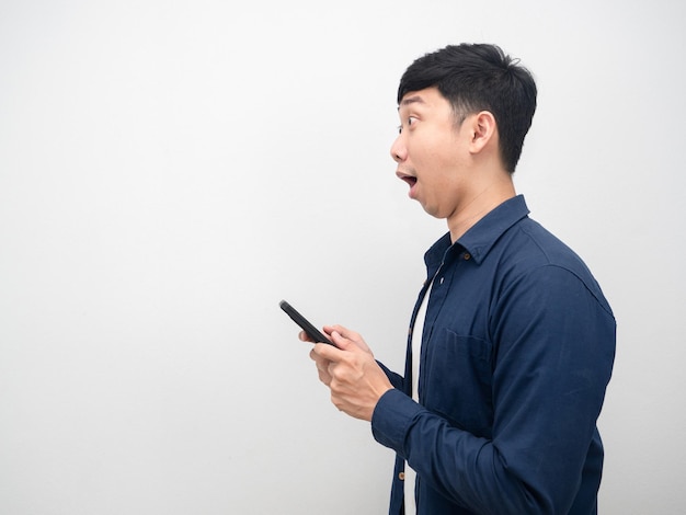 Side view man holding mobile phone excited emotion looking at copy space