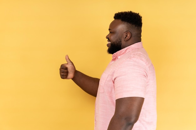 Side view of man showing thumbs up gesture doing success sign with hand approved excellent job