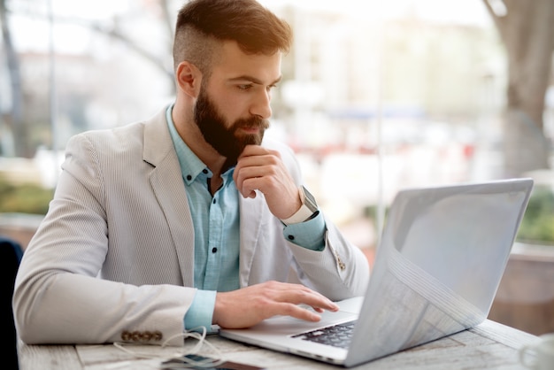 Side view of man in suit checking emails on laptop