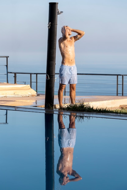 Side view man taking shower outside