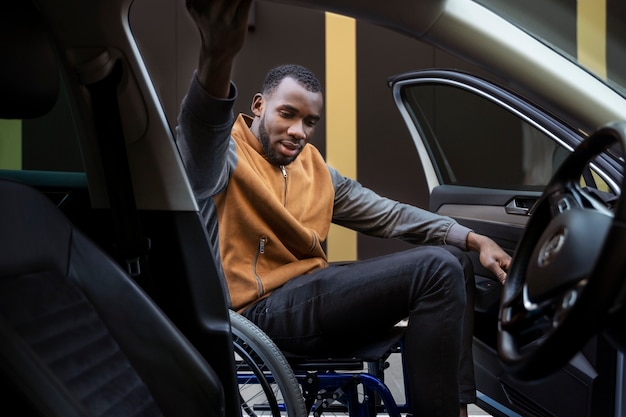 Side view man in wheelchair with car