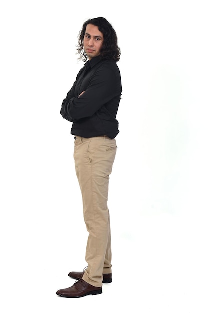 Side view of a man with long hair looking at camera and arms crossed on white background