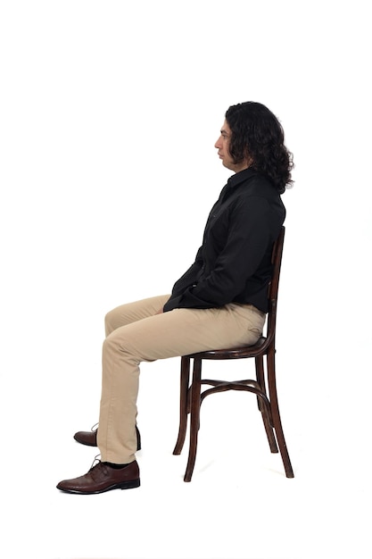 Side view of a man with shirt, shoes and pants  sitting on chair on white background