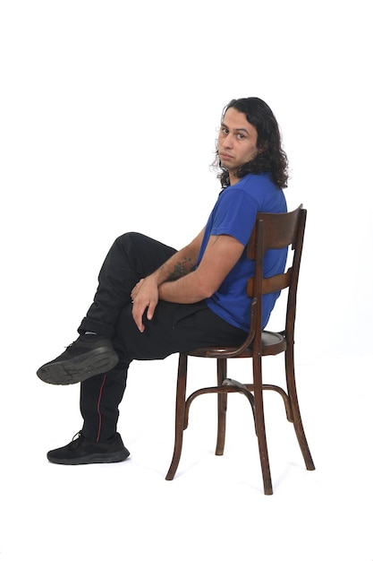 Side view of a man with sportswear sitting on chair legs on white background