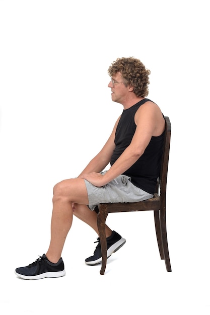 Side view of a man with sportswear sitting on chair on white background