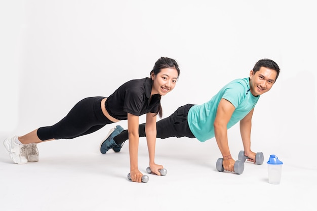 Side view of man and woman push ups with dumbbells