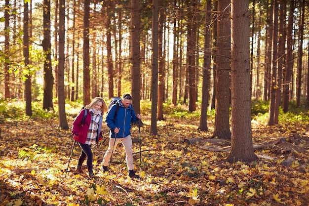 Side View Of Mature Retired Couple Walking Through Fall Or Winter Countryside Using Hiking Poles