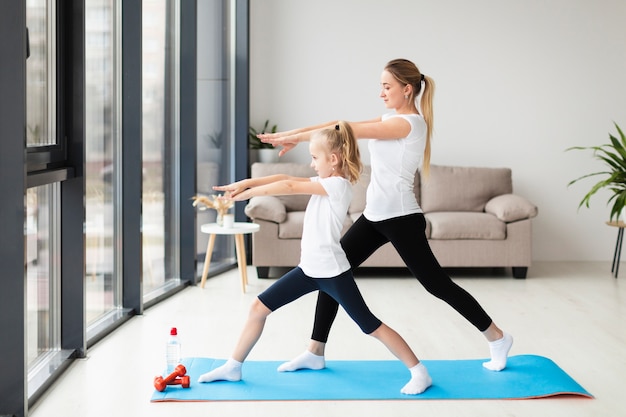 Side view of mother exercising along with child at home