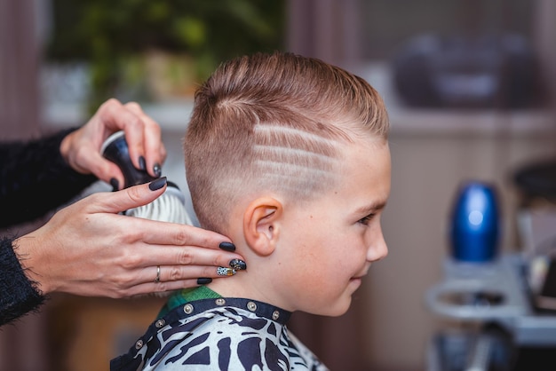 Side view Nice european boy getting hairstyle in barbershophairdresser makes a hairstyle for a boy