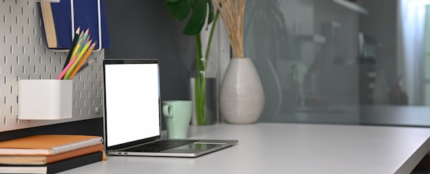 Side view of office desk with blank screen laptop, office supplies, decorations and copy space