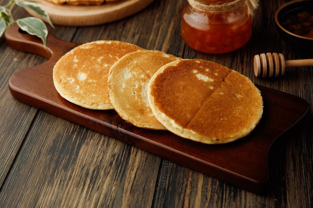 Side view of pancakes on cutting board with jam on wooden background