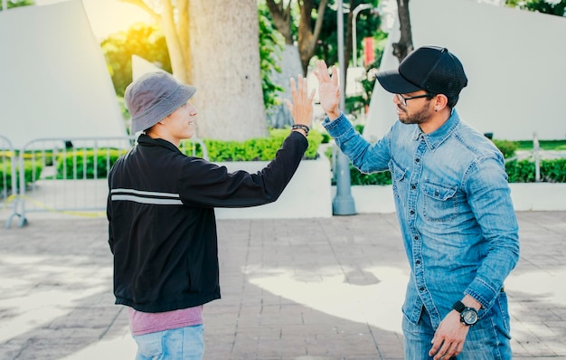 Side view of people greeting each other and shaking hands on the street Two teenage friends shaking hands outdoors Concept of two friends greeting each other with a handshake on the street