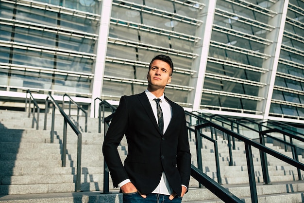 Side view photo of confident businessman in formal wear looking away while walking down on stairs