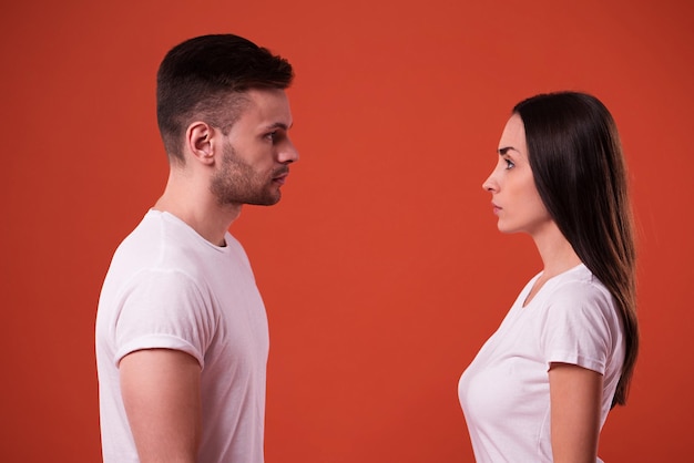 Side view photo of young serious couple standing face to face in studio