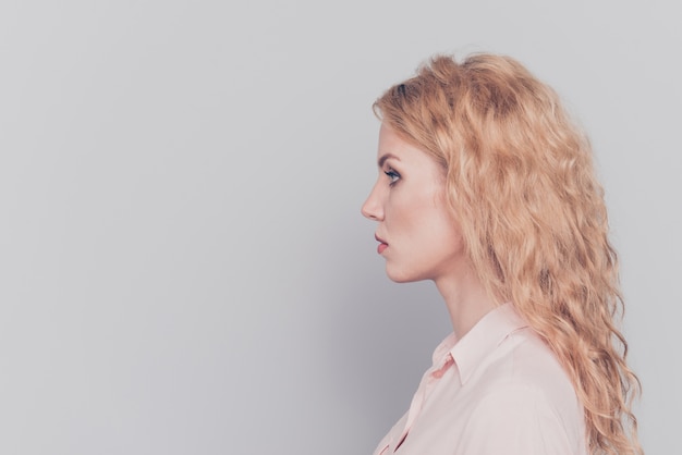 Side view portrait of attractive serious young girl isolated over grey