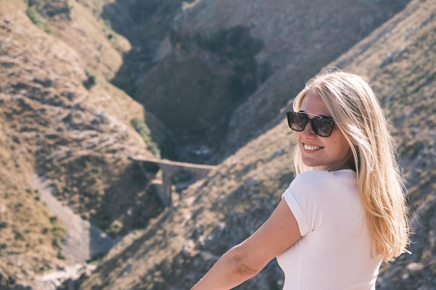 Side view portrait confident young cheerful smiling blonde woman looks into the camera wearing sungl