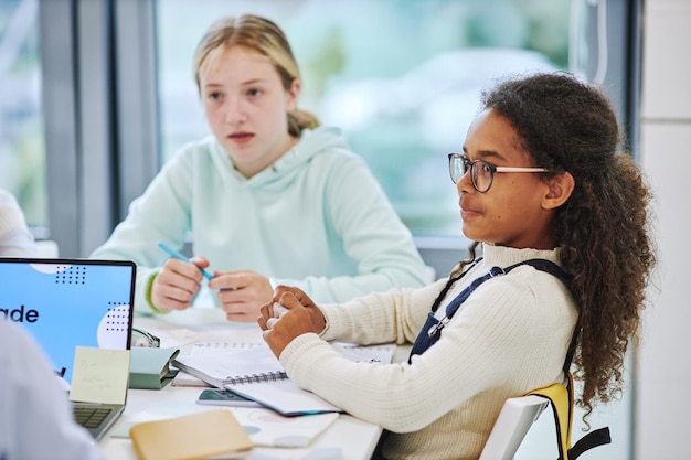 Side view portrait of cute african american girl wearing glasses in school group activity