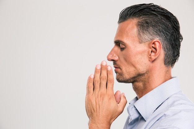 Side view portrait of a handsome man praying over gray space