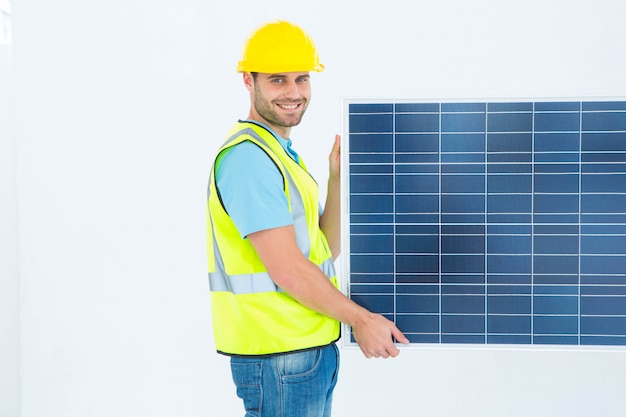 Side view portrait of happy architect holding solar panel against white background