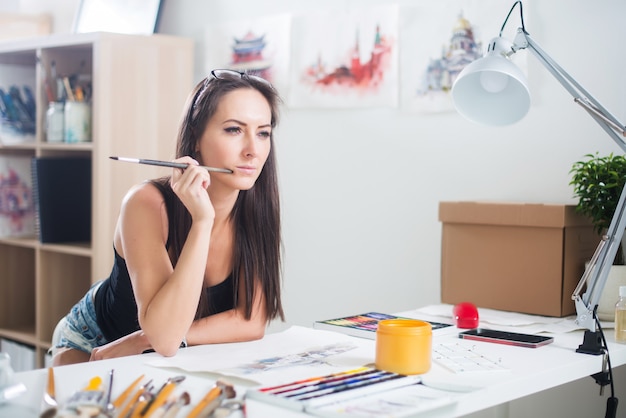 Side view portrait of a happy artist at the workplace. Young woman with paintbrush