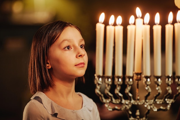 Side view portrait of young girl looking at menorah candle during hanukkah celebrations